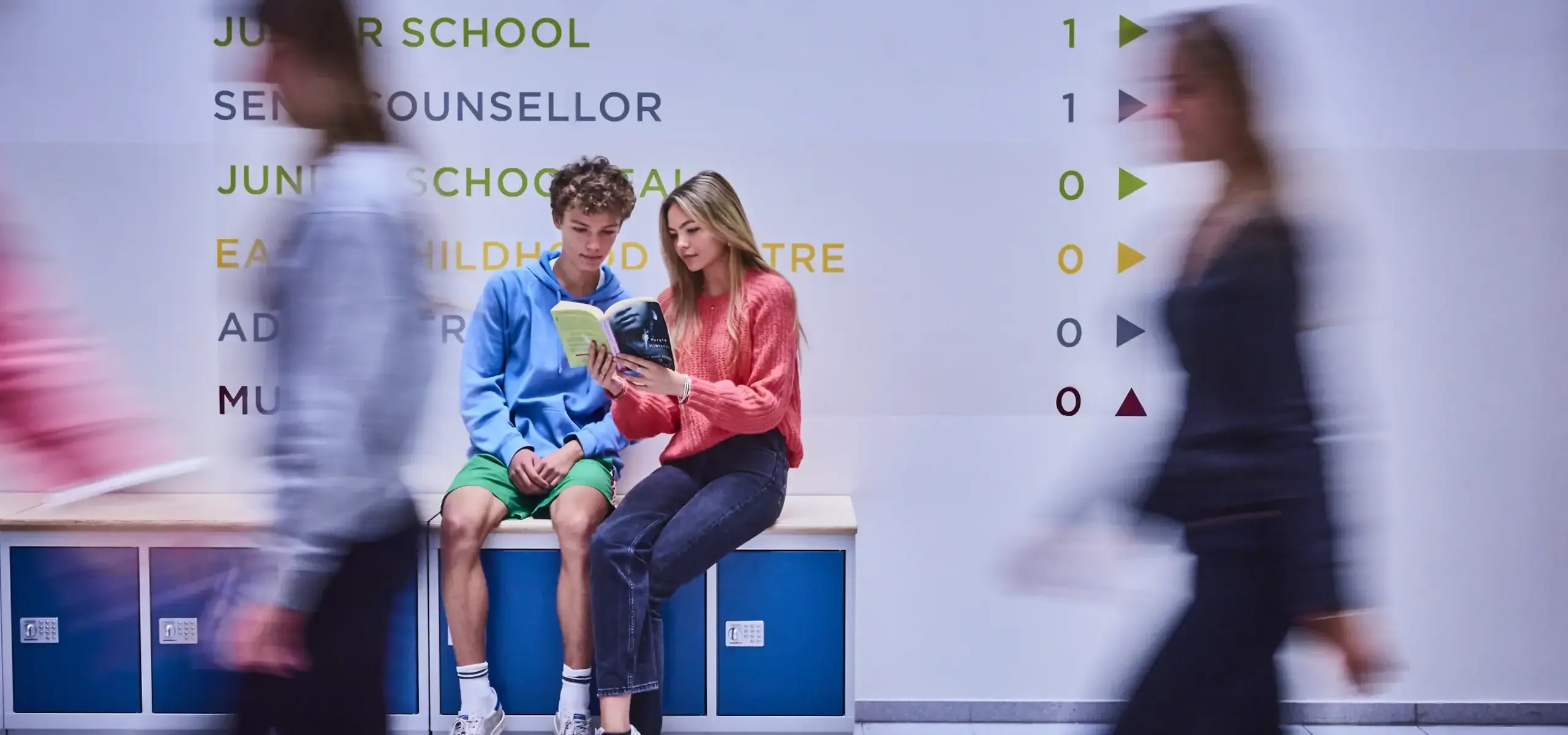 Students reading book in school foyer