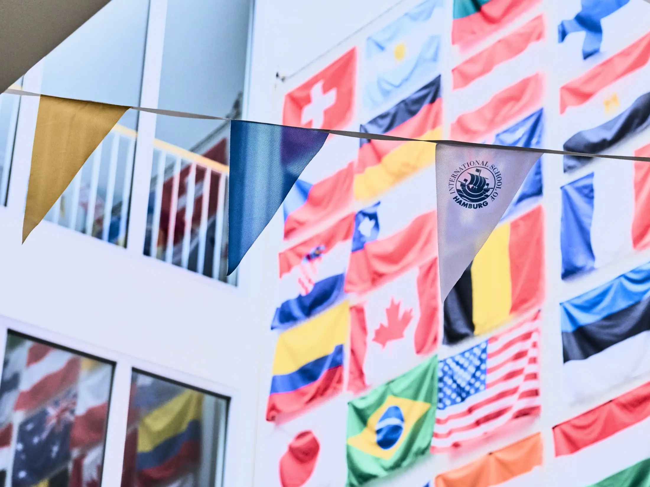 International flags fluttering outdoors against the modern building facade at International School of Hamburg
