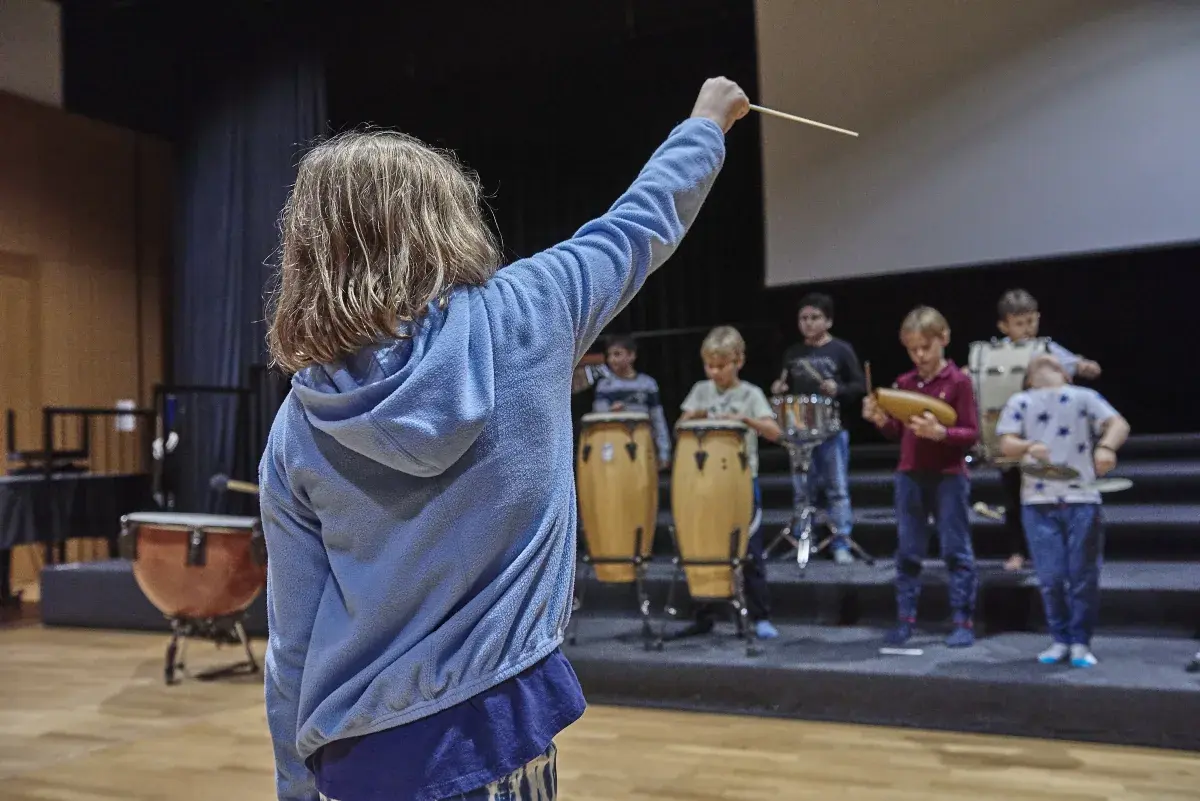 Student conducting a group of classmates playing percussion instruments during music class