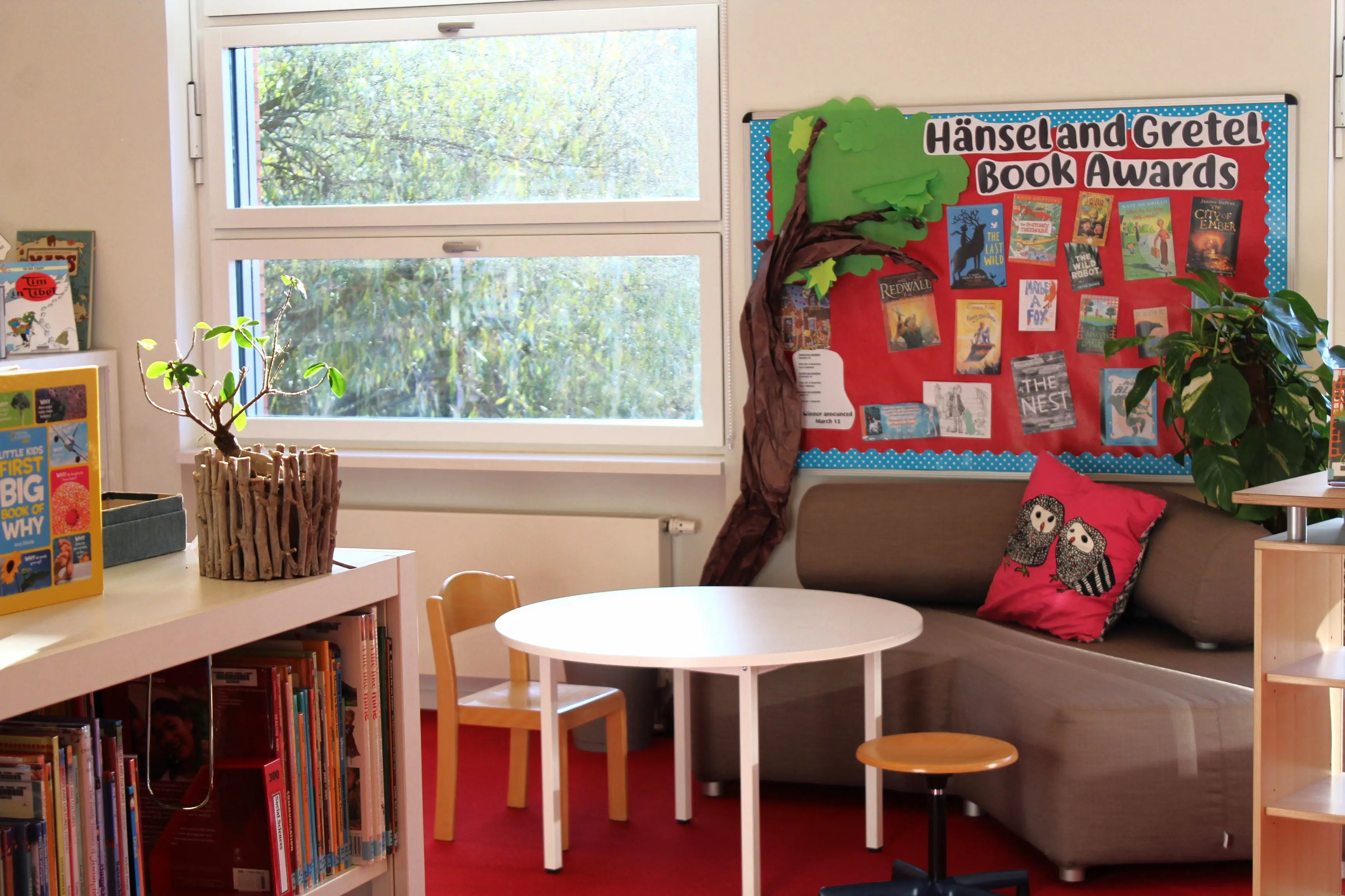 Cozy reading nook with bookshelves, table, and seating in the ISH library