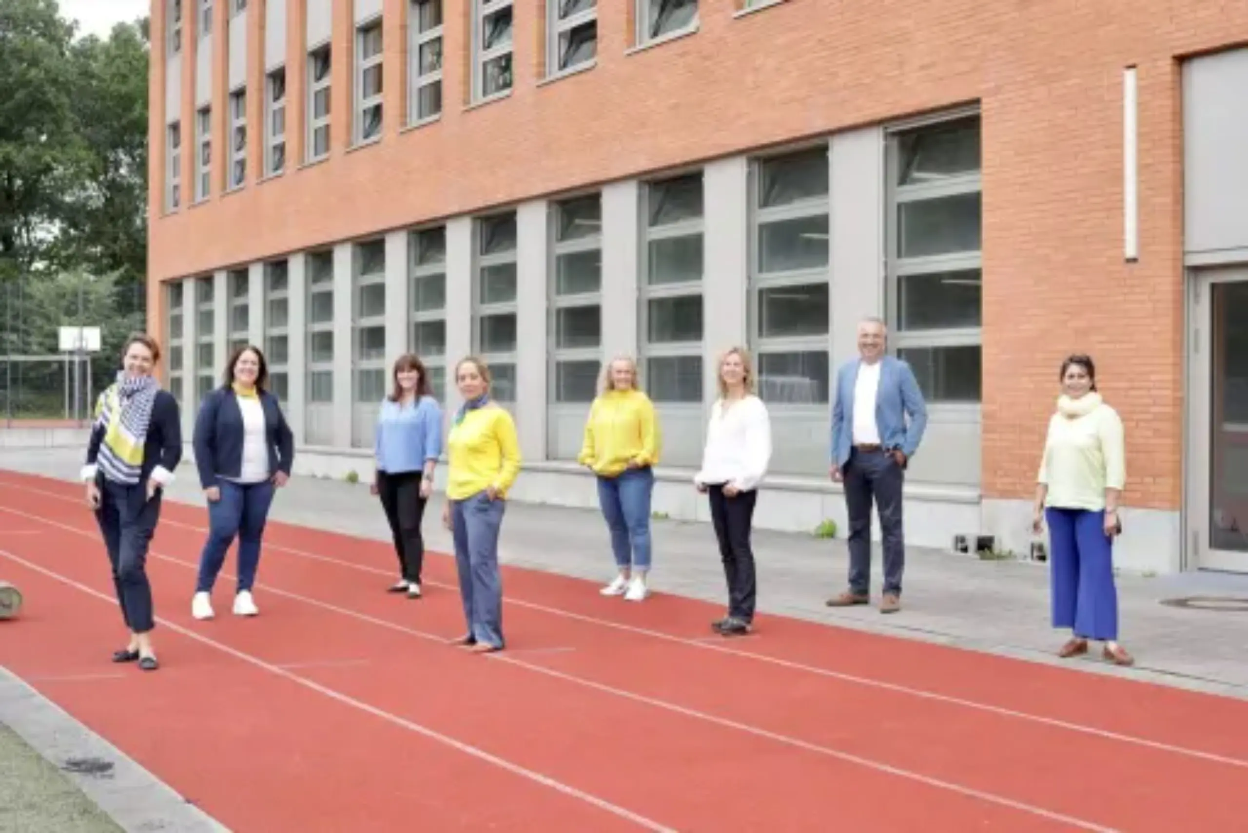 Group of International School of Hamburg staff members standing together on the outdoor running track