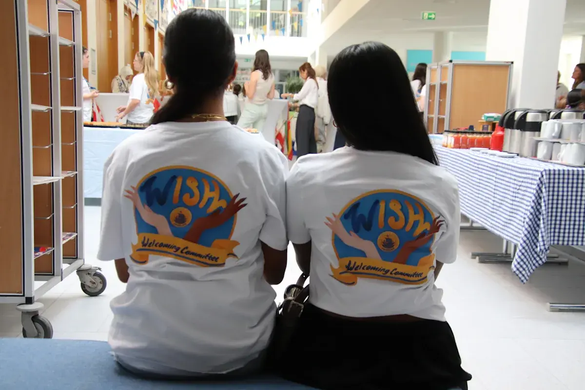 Two students sitting together wearing matching ISH t-shirts viewed from behind