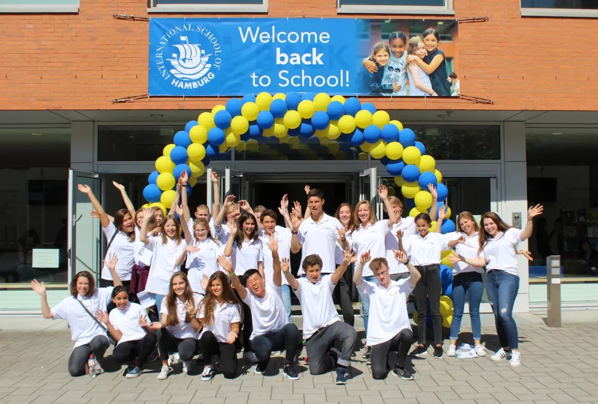 Students gathering outdoors under a yellow and blue balloon archway