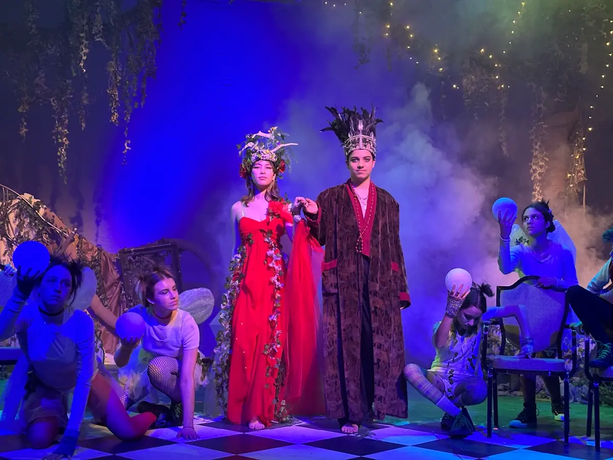 Student actors performing under stage lighting during a theatrical production