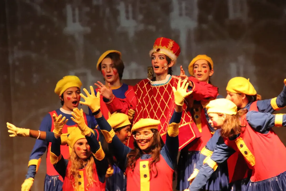 Students performing on stage in colorful theatrical costumes