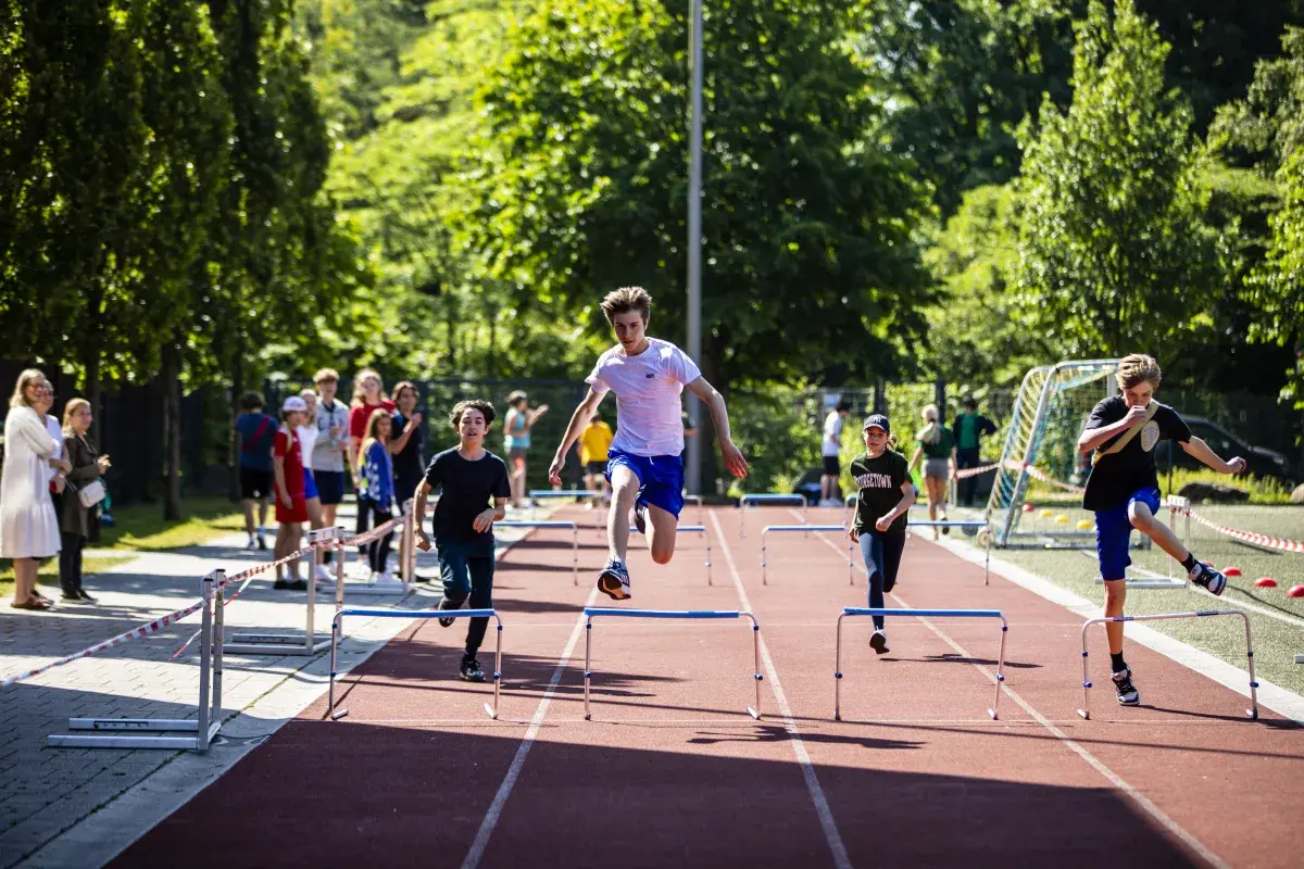 Students competing in a track and field hurdle race outdoors