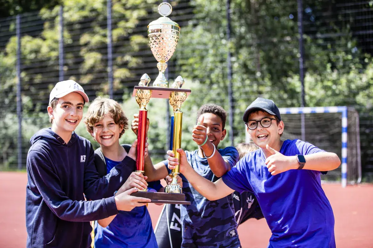 Smiling student athletes holding up a trophy outdoors