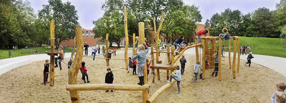Children playing on the wooden playground equipment on the ISH campus grounds